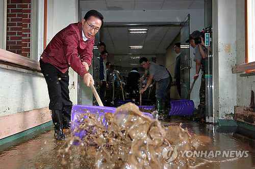 ▲ 홍수피해 지역 현장점검에 나선 이명박 대통령이 29일 경기도 광주시 초월읍 삼육재활센터에서 복구작업 참여자들과 함께 흙으로 뒤덮인 복도를 청소하고 있다.ⓒ연합뉴스