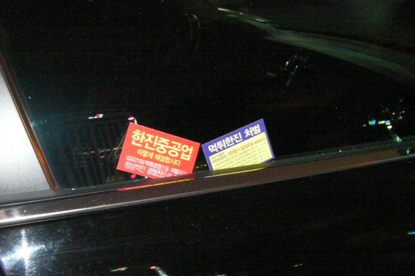 ▲ '희망버스 시위대'가 부산역 광장 주변 승용차들 문틈에 끼워넣은 '명함전단'. 사람들은 '대체 누가 생각해낸 거냐'며 혀를 찼다.