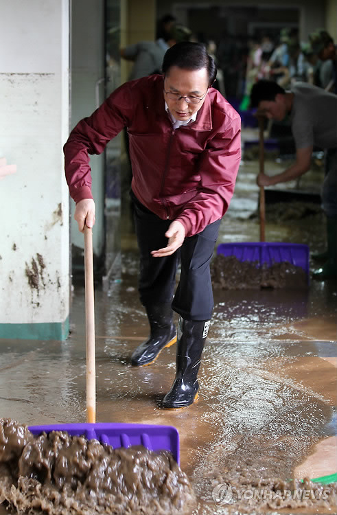 ▲ 홍수피해 지역 현장점검에 나선 이명박 대통령이 지난달 29일 경기도 광주시 초월읍 삼육재활센터에서 사람들과 함께 흙으로 뒤덮인 복도를 물청소하고 있다. ⓒ연합뉴스