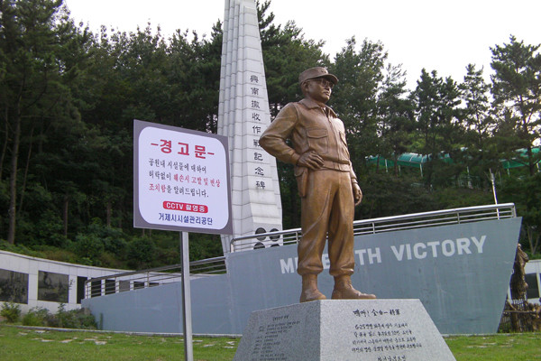 ▲ 거제포로수용소유적공원에 세워진 김백일 장군의 동상. 뒤로 보이는 조형물은 수천 명의 피란민을 태우고 흥남철수를 도왔던 전설의 상선 '메리디스 빅토리호'를 형상화한 것이다.