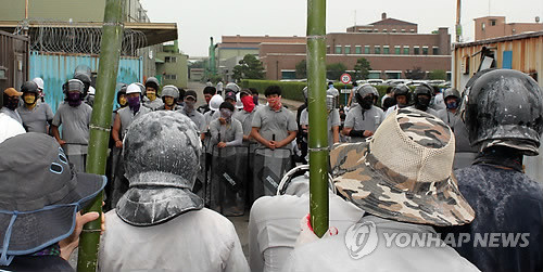 ▲ 지난 6월 유성기업 노조의 시위현장. 등을 보인 사람들이 손에 죽창을 들고 있다.[사진출처: 연합뉴스]