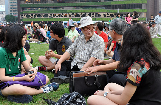 ▲ 북한 공작원 음악가 윤이상의 사주를 받아 가족과 함께 입북한 뒤 자신은 극적으로 탈출했으나 북한에 아내와 두 딸을 남겨 둔 오길남 박사가 문화제에 참석한 젊은이들과 대화를 나누고 있다.ⓒ 뉴데일리 추진혁 기자