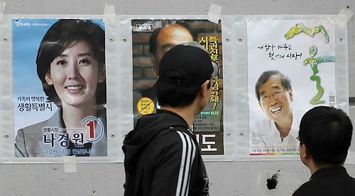 지난 16일 서울 종로구 구기동에 게시된 서울시장 선거벽보를 시민들이 유심히 살펴보고 있다. ⓒ연합뉴스