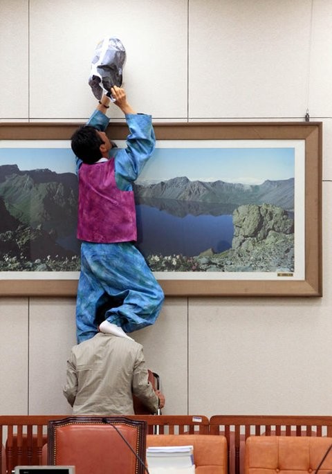 ▲ 민주노동당 강기갑 의원이 2일 오전 국회 외교통상통일위원회 회의장에서 위원장석 정면에 있는 CCTV를 신문지를 이용해 가리고 있다.ⓒ연합뉴스