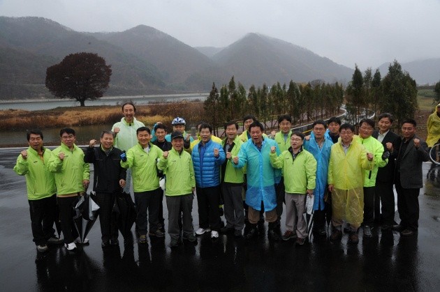 ▲ 억수 같이 쏟아지는 비를 맞으며 화천의 북한강자전거길의 시승을 마친 국토해양부 권도엽 장관 등을 비롯한 지역 유지들과 공사 관계자들이 한테 모여 거레리 수변생태공원 광장에서 개방 축하 함성을 웨치고 있다.   ⓒ 이오봉 기자