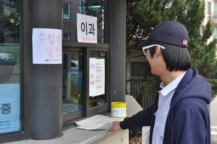 ▲ 사진 = 학교 정문 앞에 놓인 ‘수험생 유의사항’ 자료를 가져가는 한 학생의 모습이다.