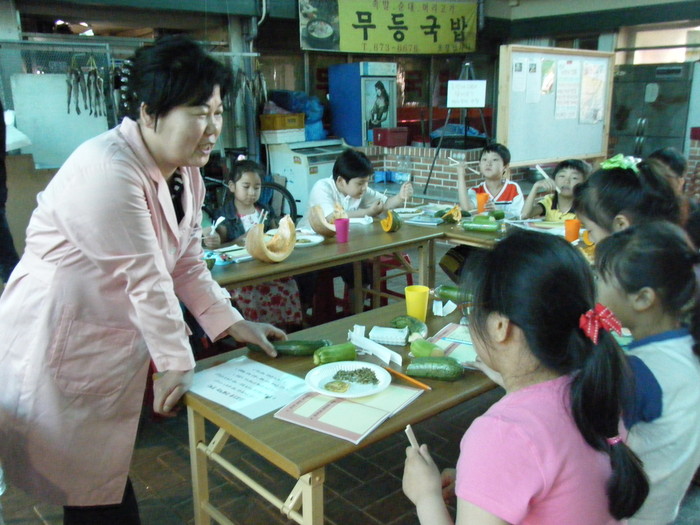 ▲ 무등시장 정남숙씨가 봉주초등학교 학생들이에게 호박을 가르치고 있다. ⓒ 시장경제신문
