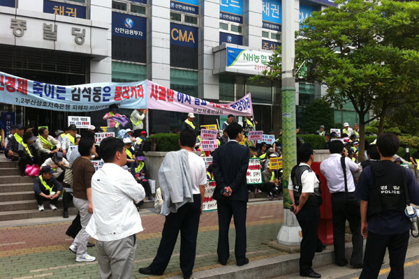 ▲ 지난 6월 20일 부산저축은행 피해비대위 회원들이 예금보험공사로부터 위임을 받은 J법무법인 앞에서 시위를 벌이고 있다. J법무법인은 결국 사건수임을 포기했다. 하지만 법무법인 부산은 부산저축은행으로부터 4년 동안 60억 원에 가까운 사건 수임료를 받은 것으로 알려졌다.