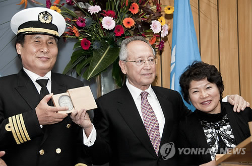 ▲ (런던=연합뉴스)21일(현지시간) 런던에 있는 국제해사기구(IMO) 총회장에서 `세계 최고 용감한 선원상(Exceptional Bravery Award at Sea)' 을 수상한 `아덴만의 영웅' 석해균 선장이 자랑스런 메달을 들어보이고 있다.  가운데는 IMO 에프티미오스 미트로폴로스 사무총장, 오른쪽은 부인 최진희씨
