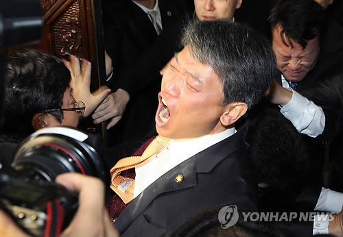 ▲ 김선동 민주노동당 의원이 지난 22일 한미 FTA 비준안 처리 당시, 국회 본회의장에 최루탄을 터뜨린 뒤 국회 경위들에게 이끌려 나오고 있다. ⓒ 연합뉴스