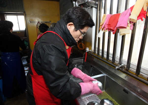 ▲ 김 지사가 식사 배식 후 고무장갑을 끼고 설거지를 하는 모습. ⓒ 뉴데일리