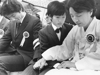 ▲ 아웅산 테러 희생자 영결식장에서 김재익 경제수석비서관의 부인 이순자 여사가 눈을 감은 채 두 아들 한회,승회 군의 손을 잡고 있다. ⓒ