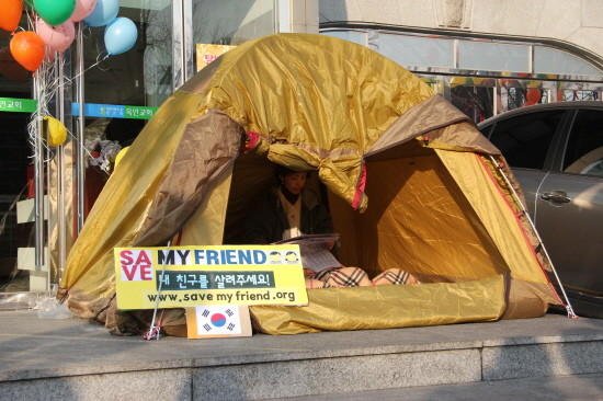 ▲ 22일 서울 중국대사관 맞은편에 설치한 텐트 안에서 신문을 보고 있다. ⓒ 뉴데일리