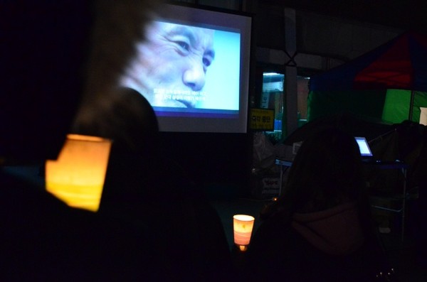 ▲ 촛불문화제에 참가해 '김정일리아'라는 북한인권다큐멘터리를 시청하고 있는 시민들.