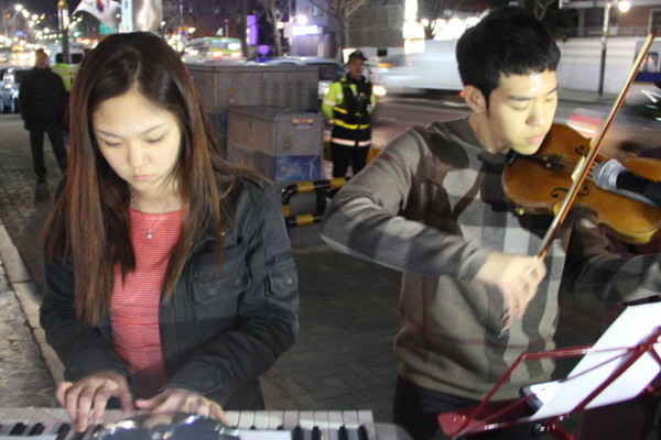 ▲ 피난처에서 인턴으로 근무하고 있는 이승재(22, 남), 서혜경(22, 여) 학생이 촛불문화제에서 각각 바이올린, 피아노를 연주하고 있다. ⓒ 뉴데일리