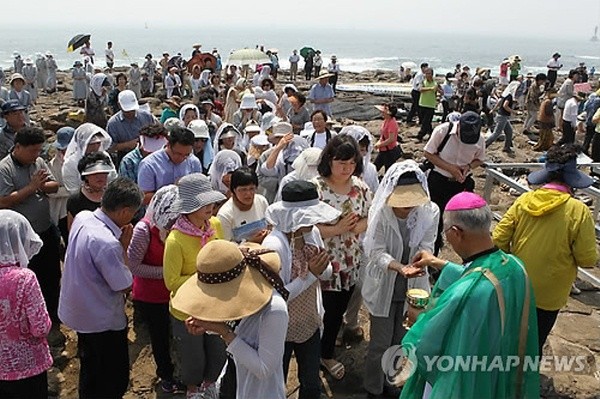 ▲ 천주교 전주교구장인 이병호 주교가 지난해 제주 해군기지 건설지인 서귀포시 강정마을 구럼비해안에서 '생명·평화 기원 미사'를 봉헌한 뒤 신자들에게 성체를 나눠주고 있다.  ⓒ 연합뉴스