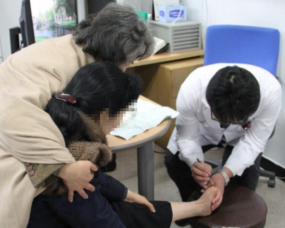 ▲ 혜민병원 정형외과 이두연 과장이 최 씨를 발을 치료하고 있다. ⓒ 뉴데일리