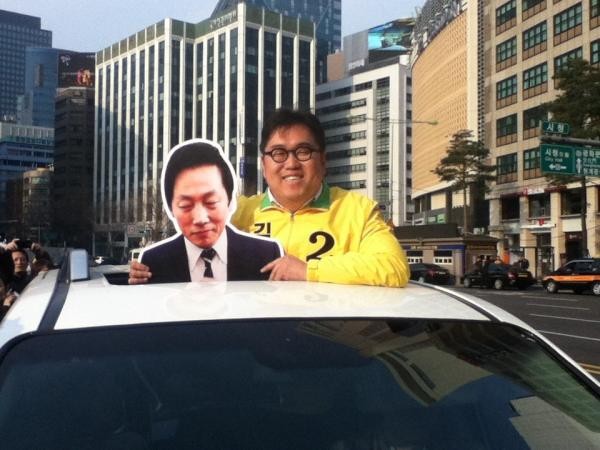 ▲ 8일 오후, 서울 시청광장에서 열린 '삼두노출' 행사에서 민주통합당 김용민 후보가 정봉주 전 의원의 얼굴이 인쇄된 피켓을 들고 있다.  ⓒ 민주통합당 김용민 후보 트위터 화면캡쳐