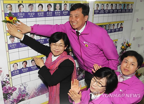 ▲ 통합진보당 이정희 대표와 당직자들이 4.11 총선에서 당선한 후보자들의 명단에 꽃을 붙이며 활짝 웃고 있다.ⓒ 사진 연합뉴스
