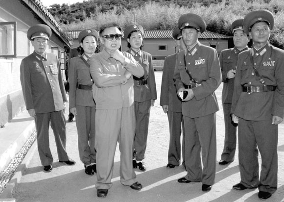 ▲ 북한이 10월 11일 공개한 김정일 국방위원장의 인민군 제 821부대 산하 여성포중대 시찰사진. 계절과 맞지 않는 배경 때문에 조작설이 제기됐다.