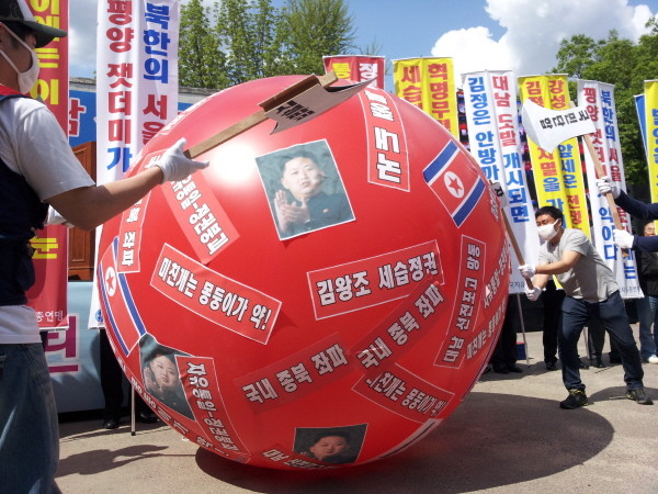 ▲ 참가자들이 김정은 사진이 붙은 대형 풍선을 도끼로 내리찍고 있다. ⓒ 뉴데일리