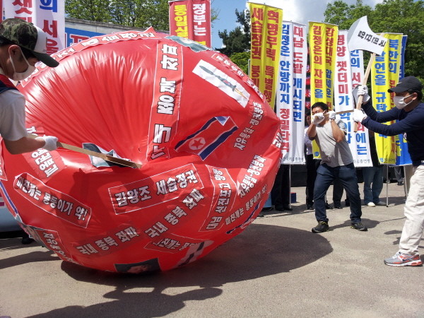 ▲ 참가자들이 김정은 사진이 붙은 대형 풍선을 도끼로 내리찍고 있다. ⓒ 뉴데일리