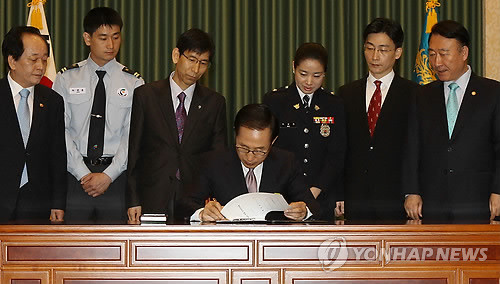 ▲ 이명박 대통령이 8일 오전 청와대에서 이국종 아주대 의대교수 등이 지켜보는 가운데 위치정보, 약사법, 응급의료법 등 5개 민생 법률 공포안에 서명하고 있다.ⓒ연합뉴스