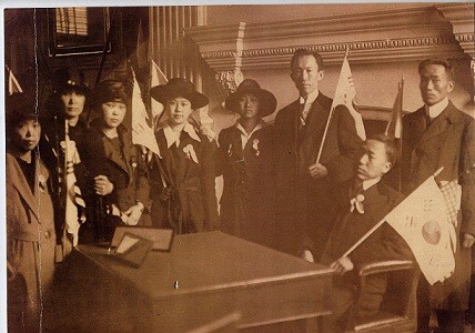 ▲ 필라델피아의 가 끝나는 날(1919년 4월 16일) 에 들어가 옛날 미국 건국대통령 워싱턴이 앉았던 자리에 좌정한 이승만. 옆에 태극기를 든 정한경, 그 옆이 노디 김양.