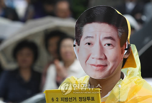 ▲ 2010년 6.2 지방선거 당시 한 민주당원이 故 노무현 대통령의 얼굴 사진을 쓰고 선거 운동을 하고 있다. ⓒ 연합뉴스