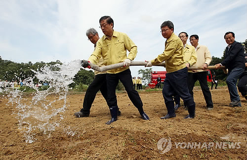 ▲ 김황식 국무총리가 26일 오전 경기도 화성시 시동 가뭄 현장을 방문, 논에 물대기 작업을 하고 있다. ⓒ 연합뉴스