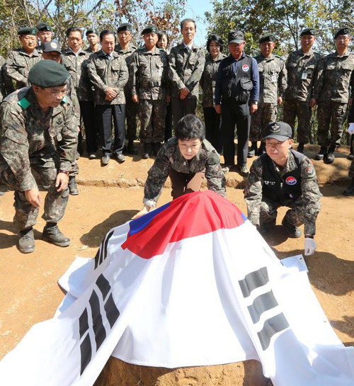 ▲ 새누리당 박근혜 대통령 후보가 25일 유해발굴단 관계자들과 함께 태극기를 펼쳐 유해를 덮고 있다. ⓒ 연합뉴스