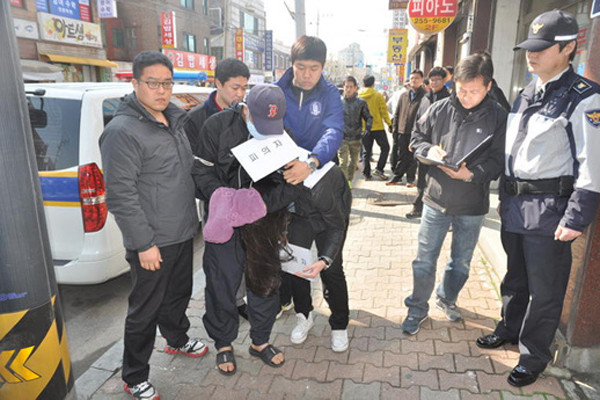 ▲ 체포된 오원춘이 경찰과 함께 현장검증을 실시하고 있다.