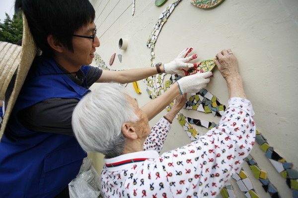 ▲ 공공미술프리즘은 2009년 5월 주민들이 참여하는 ‘우리가 만드는 우리마을’ 프로젝트의 일환으로 서울시 금천구 시흥동 혜명양로원의 벽화를 완성했다. 벽화를 함께 꾸미는 양로원 할머니와 공공미술프리즘 관계자.