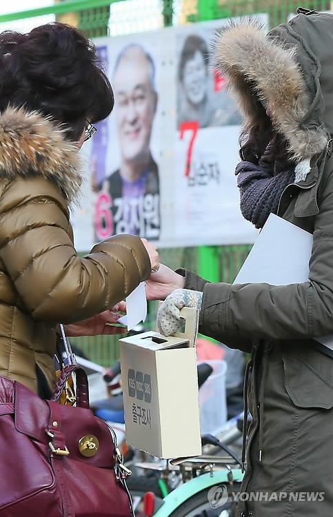 ▲ 18대 대통령선거일인 19일 서울 잠실본동주민센터에 마련된 투표소 앞에서 출구조사원들이 투표를 마치고 나오는 시민에게 출구조사를 하고 있다. 2012.12.19 ⓒ 연합뉴스