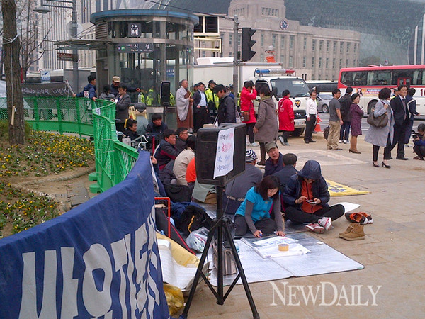 ▲ 5일 오후, 쌍용차 농성대가 천막이 있던 화단 앞에 돗자리를 깔고 구청 및 경찰과 대치를 계속하고 있다.ⓒ 뉴데일리 윤희성 기자