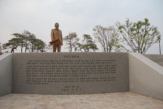 ▲ [박정희와 팝아트 투어] 행사에 참가한 한 여성이 박정희 전 대통령 생가 앞에 전시된 육영수 여사 실물 모형 옆에서 손가락 욕을 하고 있는 모습