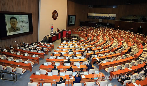 ▲ 25일 국회 본회의에서 열린 정치·외교·통일·안보 분야 대정부질문에서 김진태 새누리당 의원이 정홍원 총리를 상대로 범민련 남측본부 사이트에 올라와 있는 문건이라며 김정일의 사진을 보이며 질의하고 있다. ⓒ연합뉴스