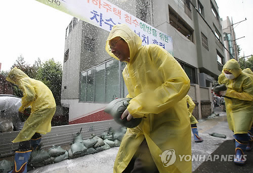 ▲ 13일 오전 서울 서초구 양재동 주택가에서 장마철 집중호우에 대비해 열린 '지하주택 침수 예방을 위한 차수판 설치 훈련'에서 참가자들이 모래주머니와 차수판을 설치하고 있다. ⓒ 연합뉴스