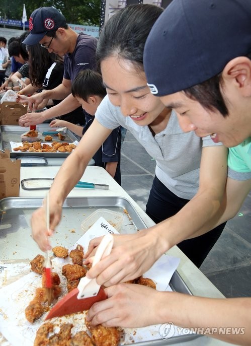 ▲ 18일 '2013 대구치맥페스티벌'이 개막한 대구 두류공원 보조경기장의 메인무대에서 시민들이 교촌치킨의 체험행사에 참여해 치킨에 소스를 바르고 포장하는 게임에 열중하고 있다. ⓒ연합뉴스