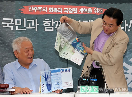 ▲ 전병헌 민주당 원내대표(오른쪽)가 9일 시청 앞 서울광장에서 열린 최고위원회의에서 정부의 세제개편안을 비난하며 유리지갑을 펼치고 있다. ⓒ연합뉴스