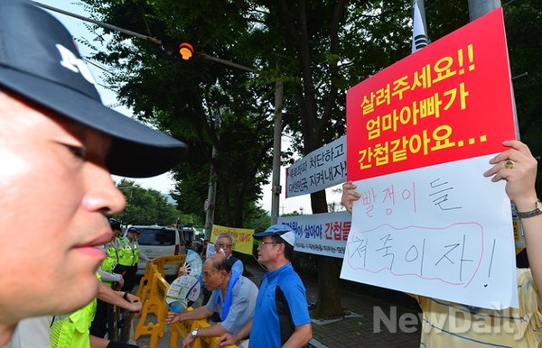 ▲ 경찰이 '종북감시단' 측의 스피커 소리에 대해서만 과태료를 부과하자 한 회원이 핸드피켓을 들며 항의하고 있다.