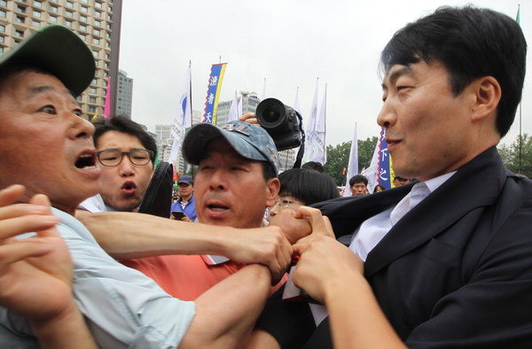 ▲ 한 농민이 한-중 FTA 중단 전국농어민대회에 참석한 통진당 이석기 의원의 멱살을 잡고 있다. 이 농민은 이석기 의원에게 "빨갱이가 여기 왜 왔느냐"며 대회장을 떠날 것을 요구했다. 이석기 의원은 농민을 향해 '씨익' 하고 비웃음을 날렸다. ⓒ연합뉴스