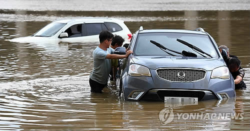 ▲ 호우로 물에 잠긴 차를 시민들이 함께 이동시키는 모습.ⓒ연합뉴스