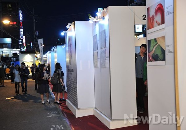 ▲ 주차장길을 걷던 학생들이 전시장에 눈길을 주고 있다.