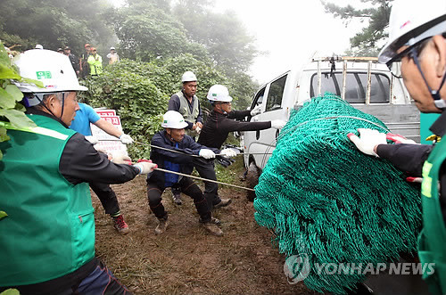 ▲ 2일 오전 경남 밀양시 부북면 위양리 126번 송전탑 공사 현장 앞에서 송전탑 시공사 관계자들이 송전탑 주변에 설치할 울타리용 자재를 옮기고 있다ⓒ연합뉴스
