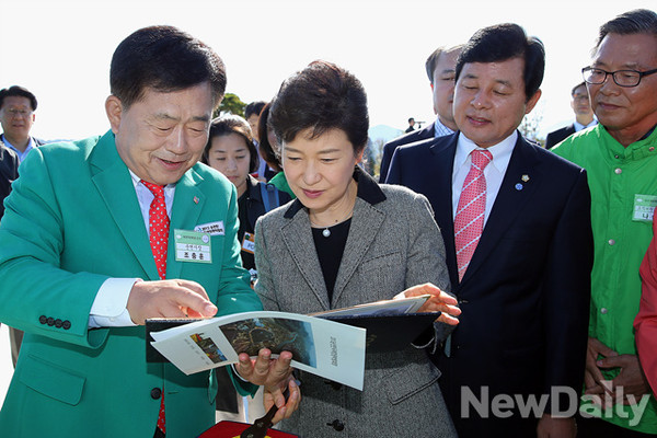 ▲ 박근혜 대통령이 20일 오전 전남 순천시 순천만 국제정원박람회장을 방문, 호수정원 해룡언덕에 올라 전시시설을 둘러보고중 조충훈 순천시장이 50여년전 순천 동천 범람 때 박정희 전 대통령 내외의 수해현장 방문 모습이 담긴 사진을 보여주고 있다. ⓒ 뉴데일리(연합뉴스)
