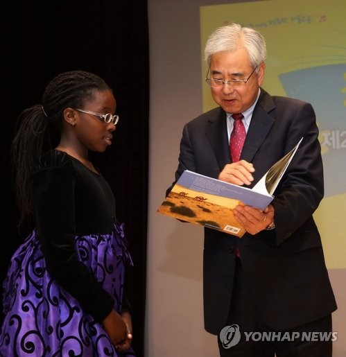 ▲ 문용린 서울교육감은 나이지리아 출신으로 이태원초 3학년에 재학 중인 이바나 양에게 책을 나눠주고 있다ⓒ연합뉴스