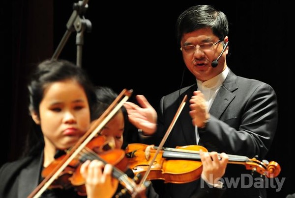 ▲ 시각장애인 이재혁 지휘자는 마이크를 이용해 오케스트라를 지휘한다ⓒ이종현