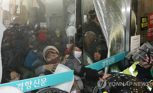 ▲ 김명환 위원장 등 철도노조 집행부에 대한 경찰의 체포영장 강제 집행이 시작된 22일 오전 서울 정동 민주노총 건물 1층에서 자동문 틈 사이로 경찰이 노조원들을 향해 최루액을 쏘고 있다.ⓒ연합뉴스