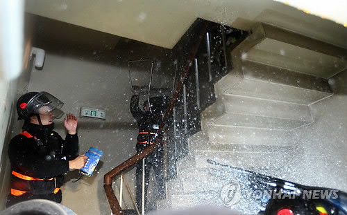 ▲ 경찰의 체포영장 집행을 노골적으로 방해한 노조원들이 경향신문사 건물 안 비상계단 위에서 진입하는 경찰들을 향해 물세례를 퍼붓고 있다.ⓒ 연합뉴스